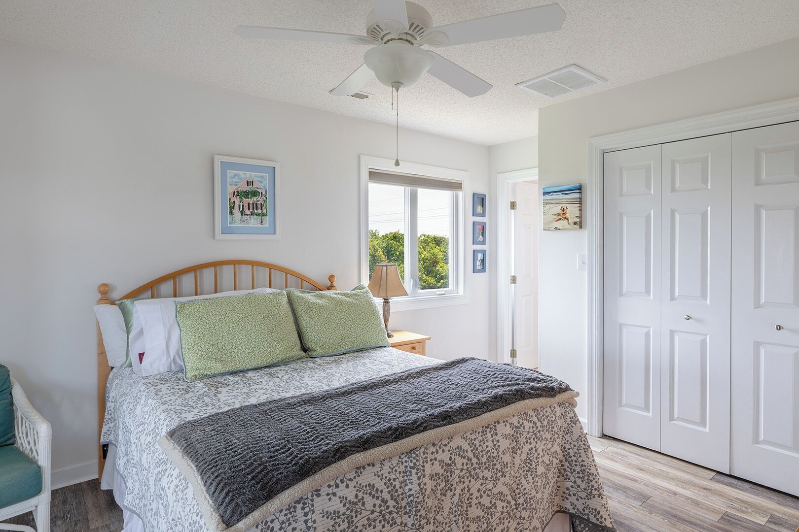 A bedroom with a bed, a nightstand, a window, and a door.
