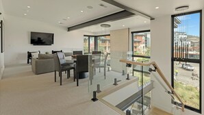 Een modern interieur met een trap, een flatscreen televisie en uitzicht op buiten.