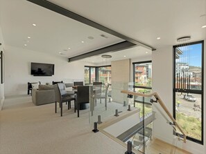 Ein modernes Interieur mit Treppe, Flachbildfernseher und Blick ins Freie.