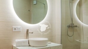 Ein Badezimmer mit rundem Spiegel, Waschbecken und Dusche.