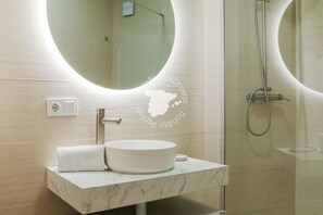 Ein Badezimmer mit rundem Spiegel, Waschbecken und Dusche.