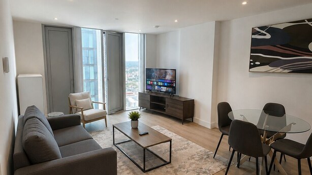 Uma sala de estar moderna com sofá, mesa de centro, televisão e área de jantar.
