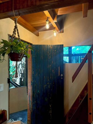 Ein Zimmer mit Holzbalkendecke, einer hängenden Pflanze, einer Tür im rustikalen Stil und einer Treppe.