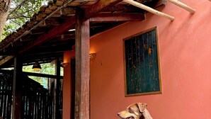 A dog sitting on a concrete floor with a wooden structure overhead. - Cozy, comfy house in the heart of Caraíva - fully equipped and peaceful located (Caraíva)