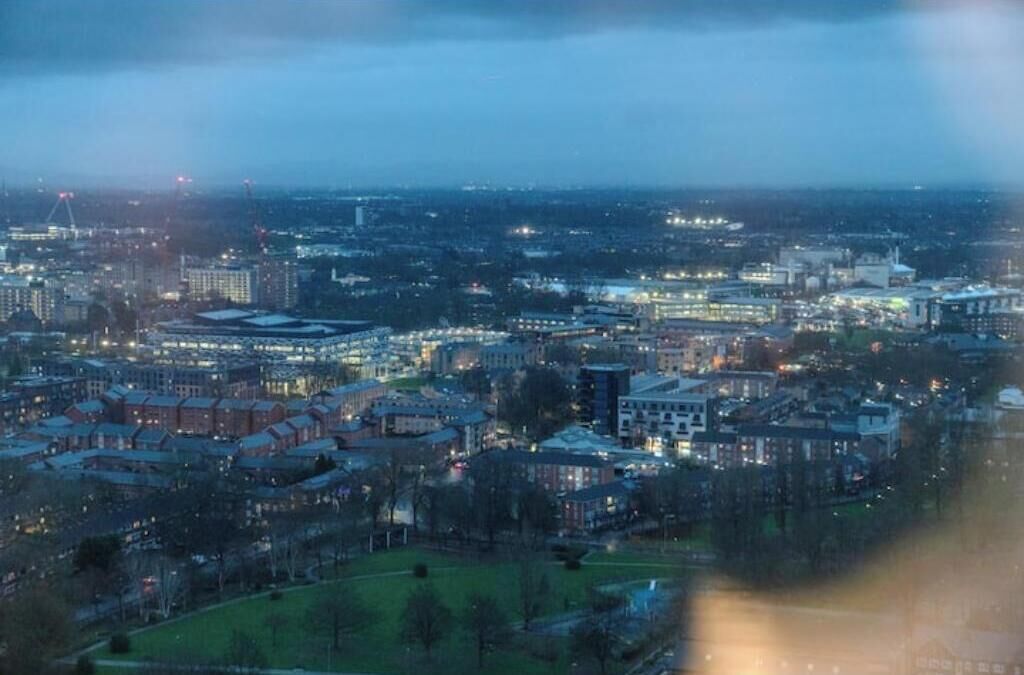 A cityscape at dusk with buildings and streets illuminated.