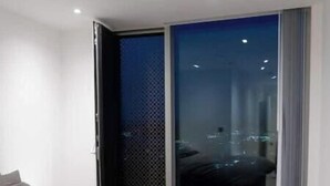 A modern bedroom with a large bed, a sliding glass door leading to a balcony, and a city view. - Modern 2-Bed Penthouse in Deansgate | Stunning City Views (Manchester)