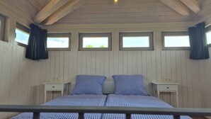 Et værelse med en seng, to sengeborde og tre vinduer med gardiner.