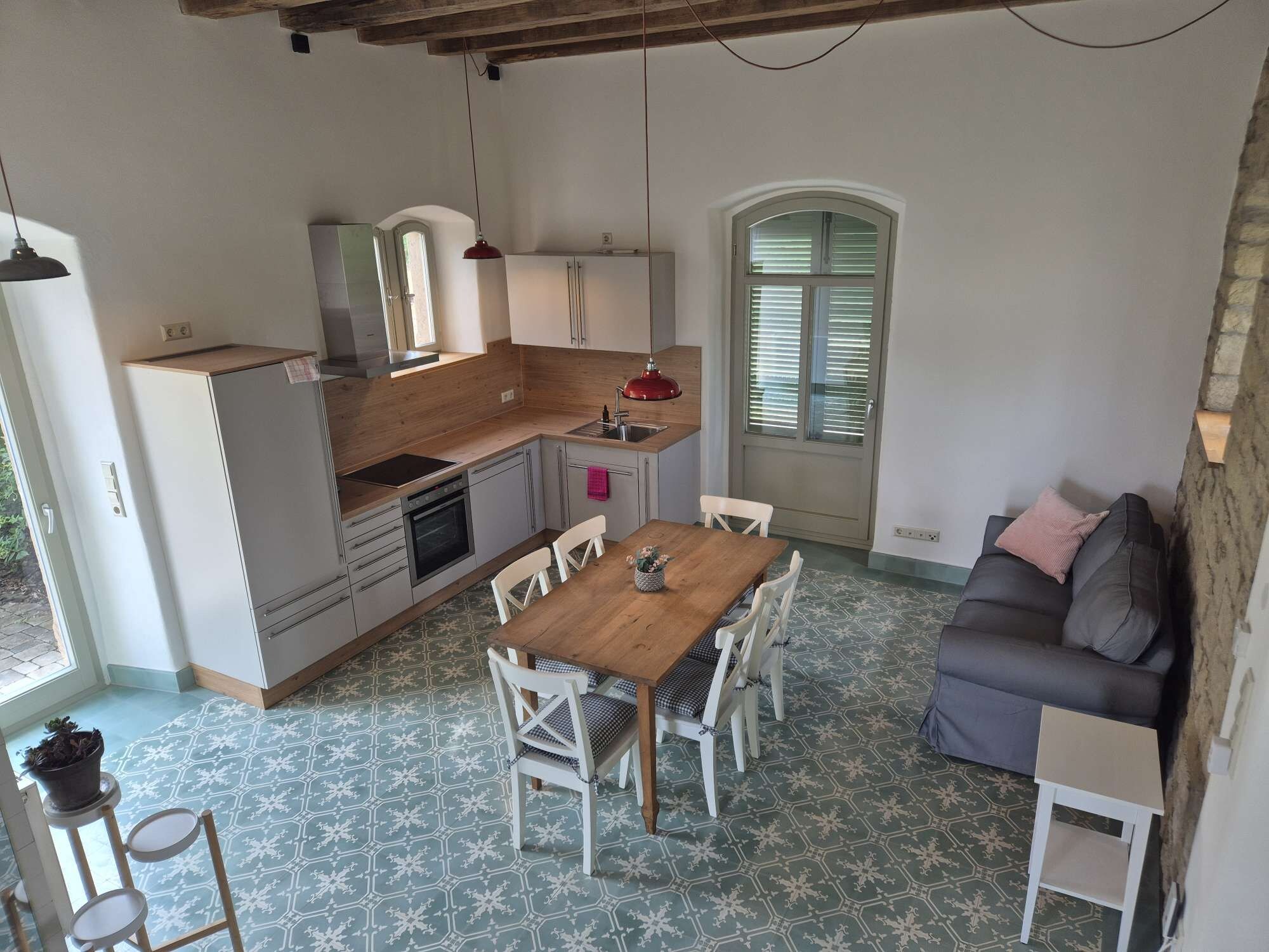 Uma cozinha compacta com área de refeições, forno embutido e janela com persianas.