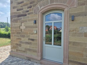 Ein Steinhaus mit einer Tür, einem Zahlenschloss und einem kleinen Fenster.