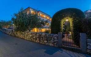 A multi-story hotel with a stone wall and a gated entrance. - Villa Milčetić Nr. 2 (Malinska)