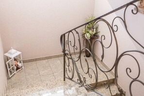 Eine Treppe mit Metallgeländer, einem Blumentopf und einem weißen Laternenlicht auf der linken Seite.