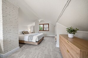 A bedroom with a loft-style ceiling, a bed, a wooden dresser, and a potted plant. - MINNeSTAY* Magnolia House (Minneapolis)