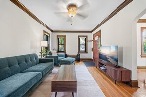 Een woonkamer met een bank, een salontafel, een televisie en een plafondventilator.