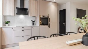 Eine moderne Küche mit hellen Holzschränken, einer eingebauten Mikrowelle, einem Backofen und einem Essbereich mit Tisch und Stühlen.
