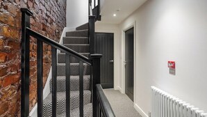 Eine Treppe mit schwarzen Geländern und einem gemusterten Teppich, die zu einer Tür führt.
