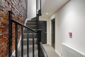 Eine Treppe mit schwarzen Geländern und einem gemusterten Teppich, die zu einer Tür führt.