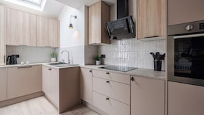 Eine moderne Küche mit hellen Holzschränken, einer schwarzen Mikrowelle und einem Edelstahlbackofen.