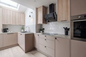 Eine moderne Küche mit hellen Holzschränken, einer schwarzen Mikrowelle und einem Edelstahlbackofen.