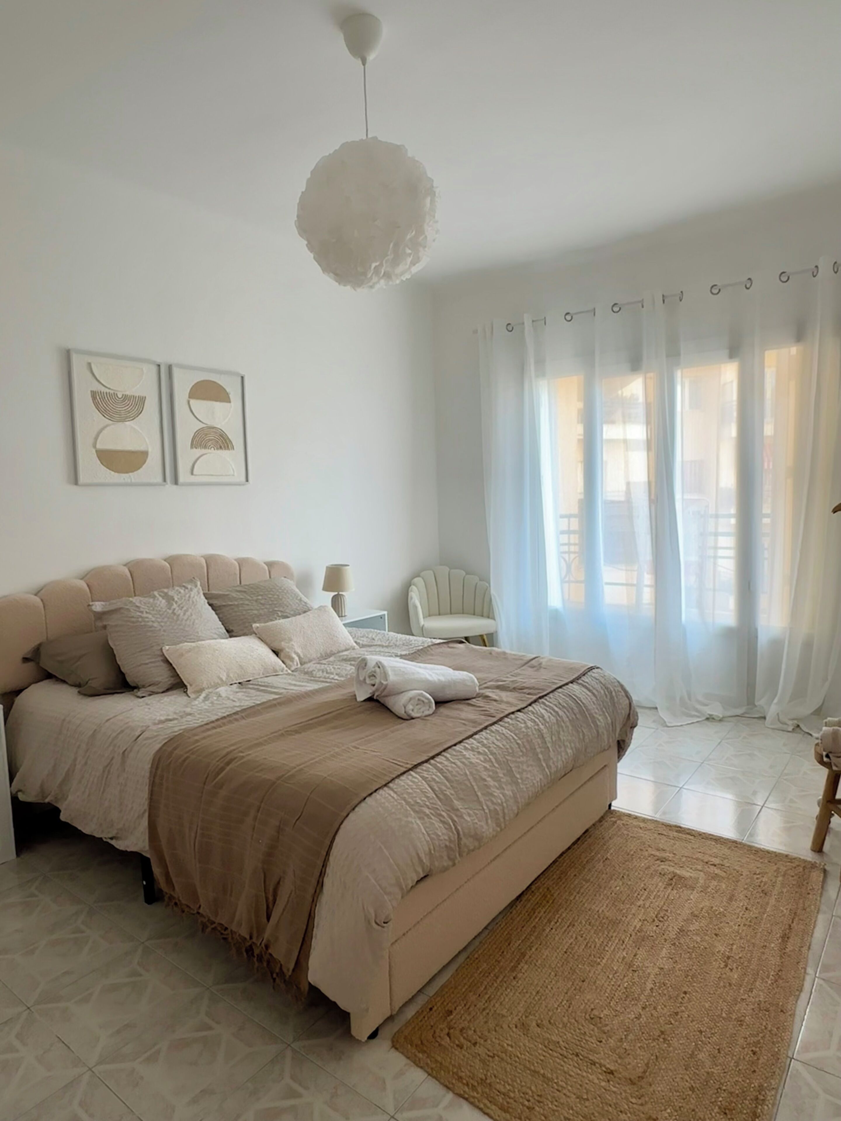A bedroom with a bed, a bedside table, a chair, and a window with curtains.
