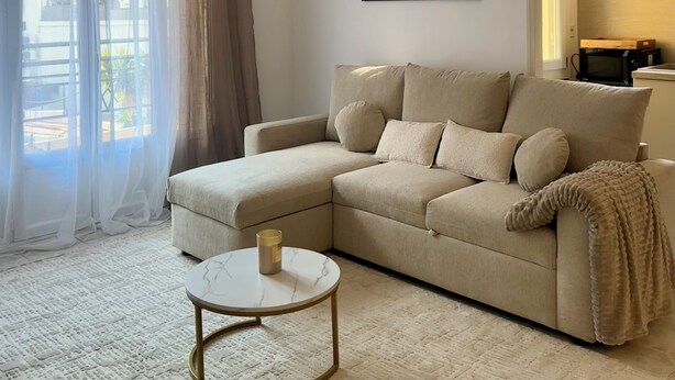 Ein Wohnzimmer mit einer Couch, einem runden Couchtisch und einer Pendelleuchte.