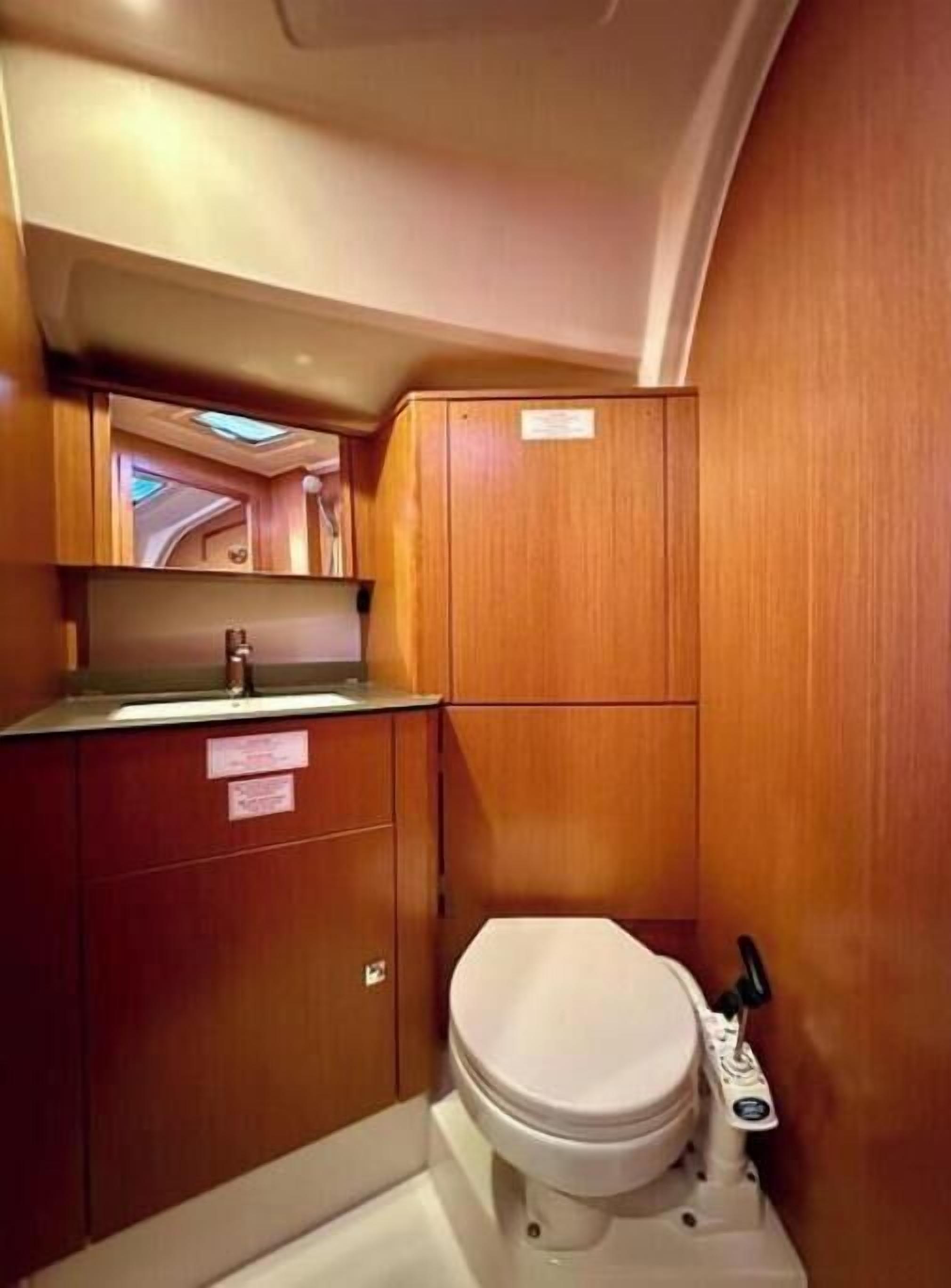 A compact bathroom with a toilet, a sink, and wooden cabinetry.