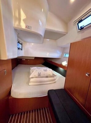 A compact cabin with a bed, a bench, and a small seating area. - Bavaria Cruiser 41 - Zubatac (Dalmacija Marina)