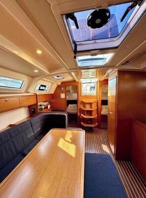 A compact interior with a dining area, a seating area, and a passage leading to an external deck. - Bavaria Cruiser 41 - Zubatac (Dalmacija Marina)