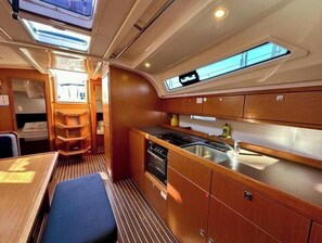 A compact galley with a sink, stove, and storage cabinets. - Bavaria Cruiser 41 - Zubatac (Dalmacija Marina)