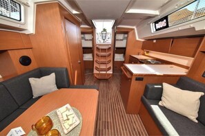 A compact interior with a dining table, two sofas, a small kitchen area, and a central seating area with a view.