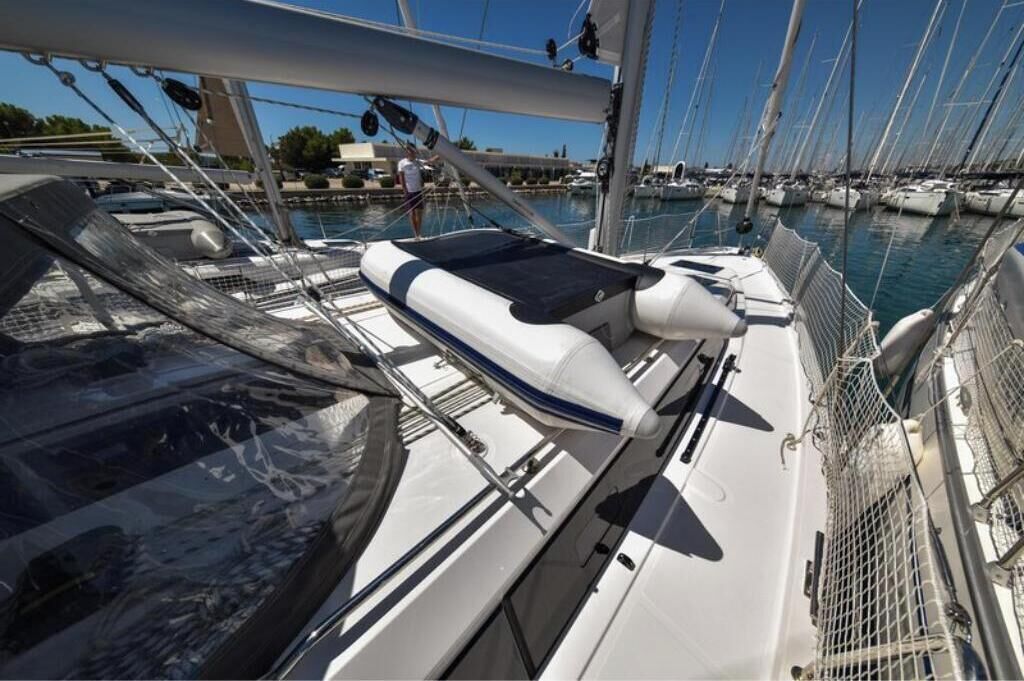 Un puerto deportivo con barcos amarrados, una persona de pie en una embarcación y un cielo despejado.