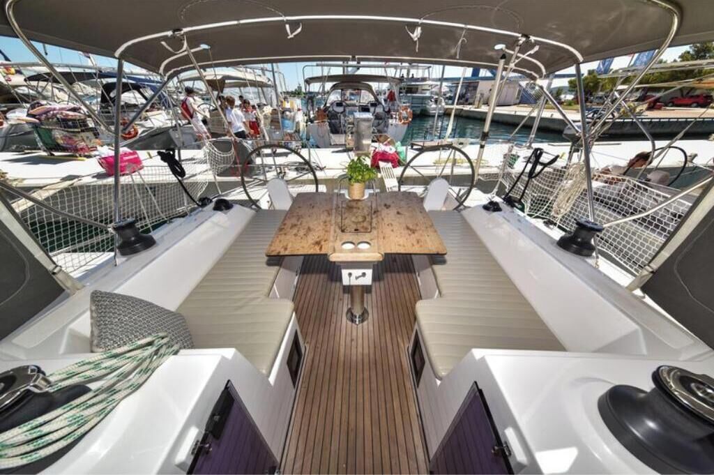 A boat deck with a central table, seating, and a view of the marina.