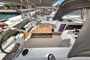 A boat deck with a table, seating, and a small plant.