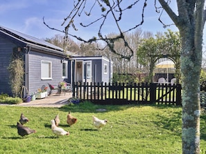 Una casa con patio cercado, pequeño jardín y zona de patio con mobiliario exterior.
