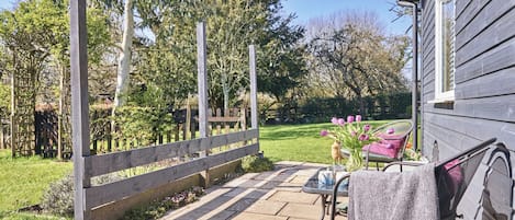 A patio with a wooden fence, a table with a chair, and a house in the background.