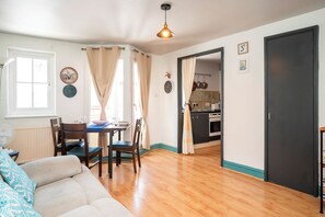 A cozy living room with a sofa, dining table, chairs, and a kitchen area with cabinets and a stove. - Comfortable Stay in the Heart of Vibrant Deptford - Pass the Keys (London)