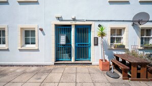 A building with a blue door, a satellite dish, and a small garden area with a bench. - Comfortable Stay in the Heart of Vibrant Deptford - Pass the Keys (London)