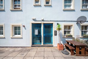 A building with a blue door, a satellite dish, and a small garden area with a bench. - Comfortable Stay in the Heart of Vibrant Deptford - Pass the Keys (London)