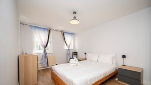 A bedroom with a wooden bed, a nightstand, a dresser, and a window with curtains. - Comfortable Stay in the Heart of Vibrant Deptford - Pass the Keys (London)