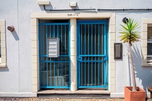 A building entrance with two blue doors, a small air conditioning unit, and a potted plant. - Comfortable Stay in the Heart of Vibrant Deptford - Pass the Keys (London)