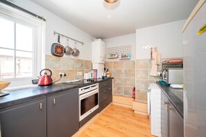 A modern kitchen with a built-in oven, a kettle, and a microwave. - Comfortable Stay in the Heart of Vibrant Deptford - Pass the Keys (London)