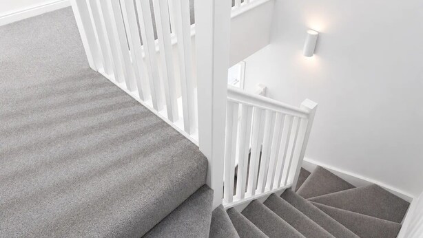 Eine Treppe mit grauem Teppich und weißen Geländern.