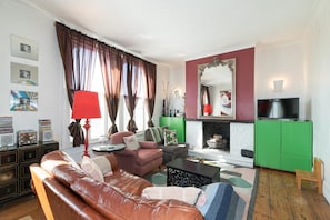 Ein Wohnzimmer mit einer Ledersofa, einem Couchtisch, einem Kamin, einem Fernseher und einem grünen Schrank.