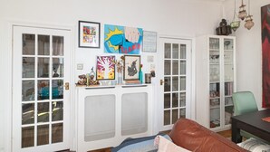 A living room with a brown leather sofa, a white cabinet with glass doors, and various framed artworks on the wall. - Charming Victorian House, Selhurst Park, London - Pass the Keys (London)