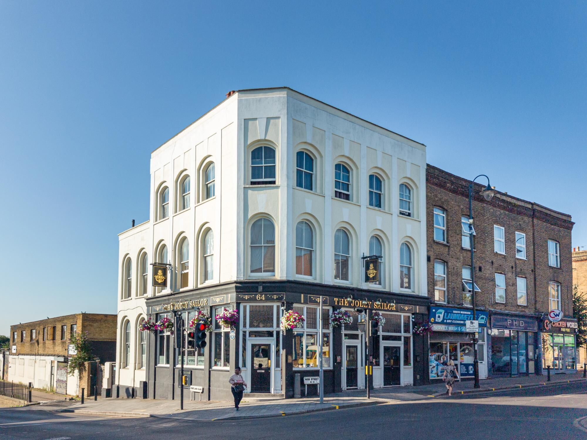 A corner building with a pub named 'The Jolly Sailor' and a sign for 'PHD.'