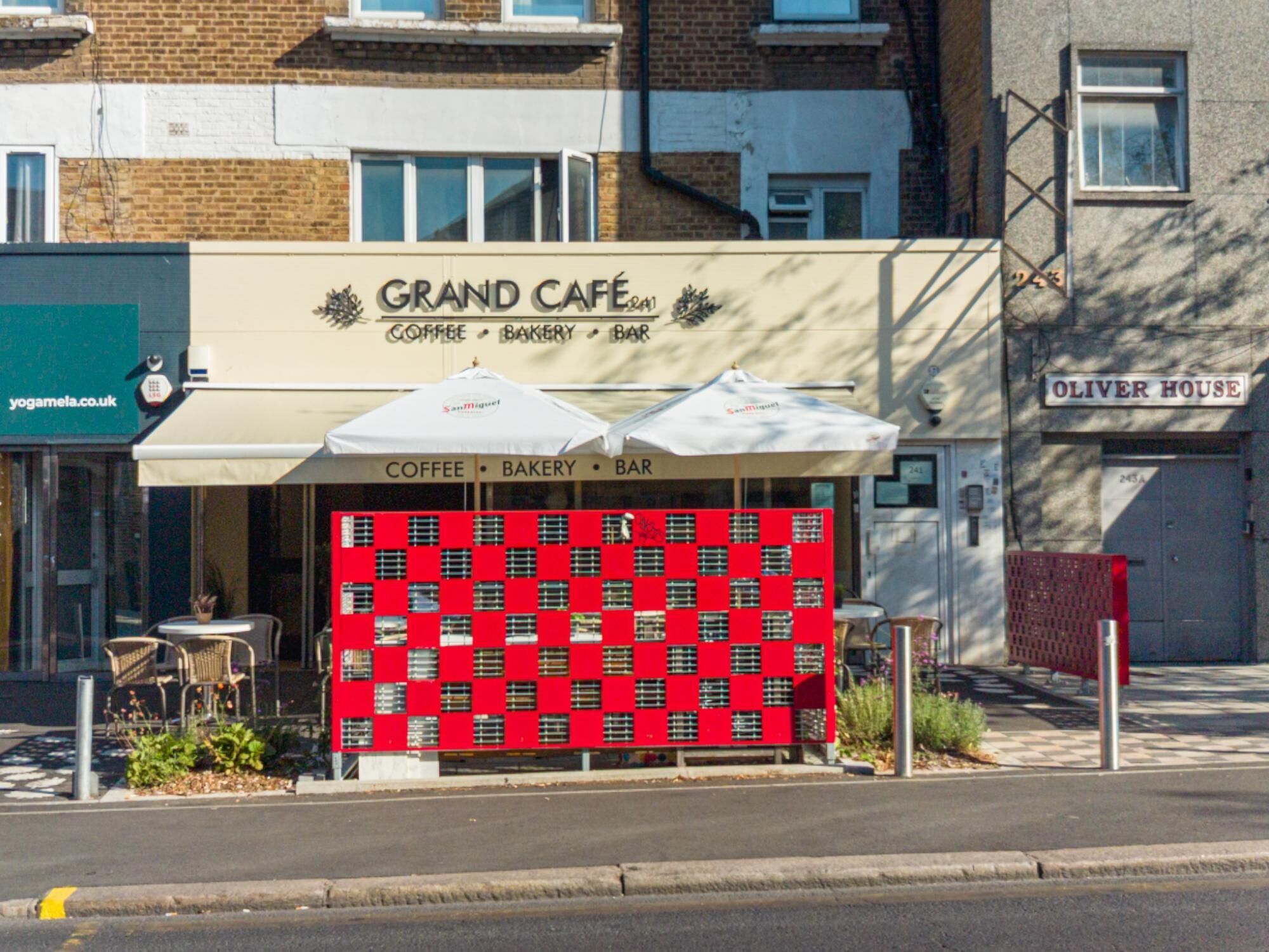 A street view of a building with a sign for 'Grand Café' offering coffee, bakery, and bar services.