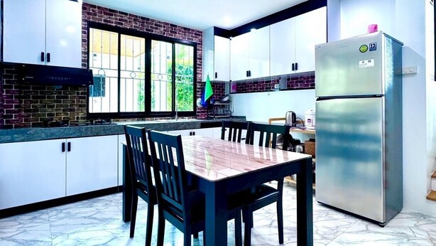 Een moderne keuken met een marmeren vloer, een eettafel met stoelen en een koelkast.