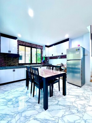 A modern kitchen with a marble floor, a dining table with chairs, and a refrigerator. - Ao nang Private Rooftop Poolvilla (Tambon Ao Nang)