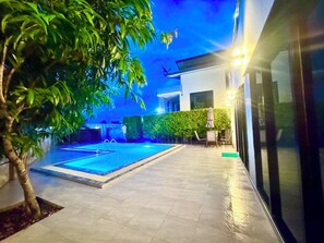 A swimming pool with a tiled deck, surrounded by greenery and a modern building. - Ao nang Private Rooftop Poolvilla (Tambon Ao Nang)