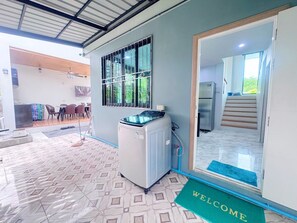 A room with a washing machine, a door with a welcome mat, and a view of a staircase leading to another room. - Ao nang Private Rooftop Poolvilla (Tambon Ao Nang)