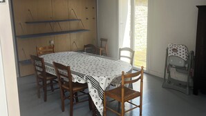 Uma área de refeições com mesa, cadeiras, uma luminária no teto e uma janela.